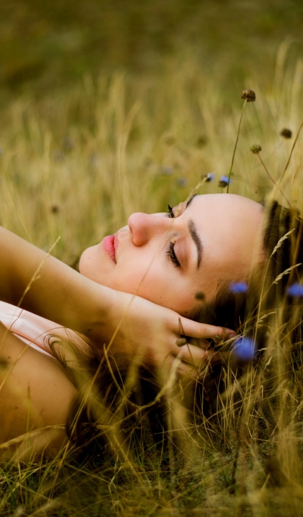 Милая девушка лежит на траве на поле