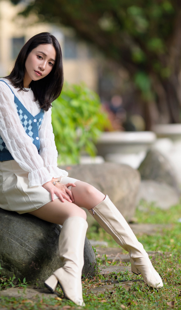 Милая девушка сидит на камне в парке