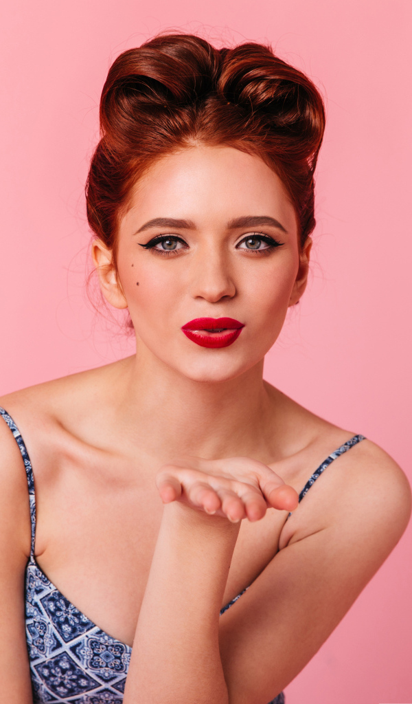 Милая рыжеволосая девушка на розовом фоне