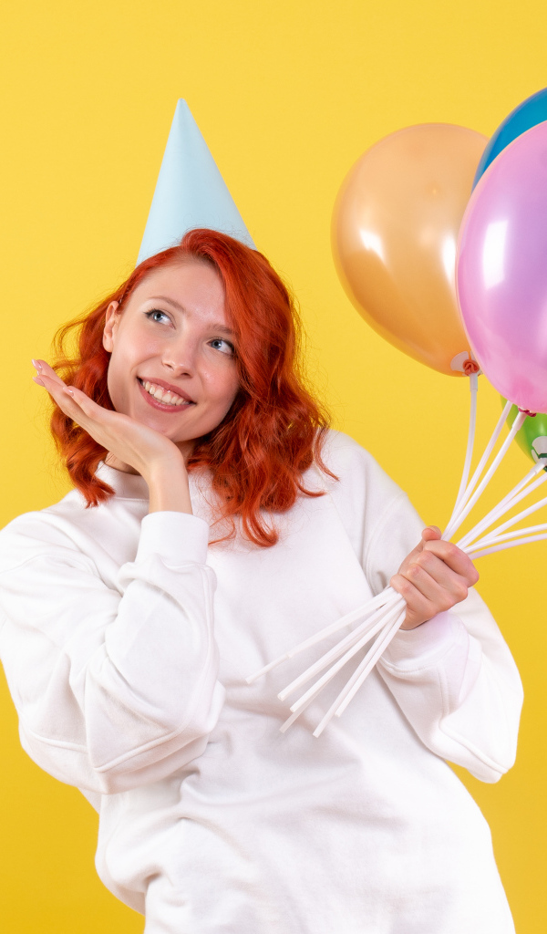 Милая рыжеволосая девушка с шариками на желтом фоне