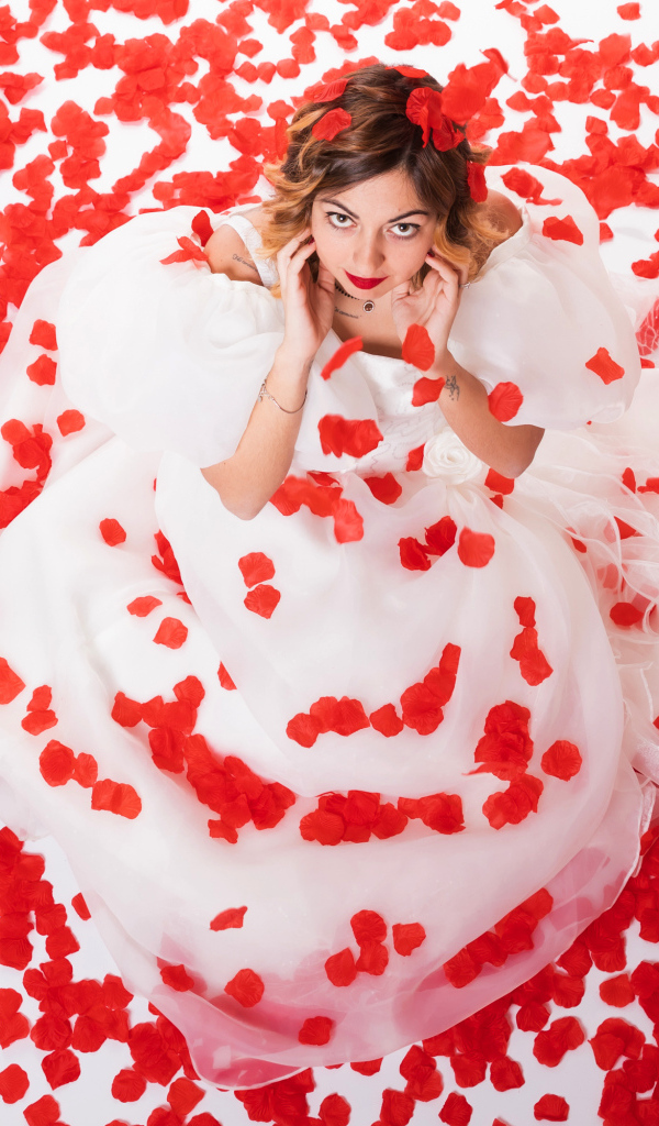 Девушка в белом платье сидит на лепестках розы