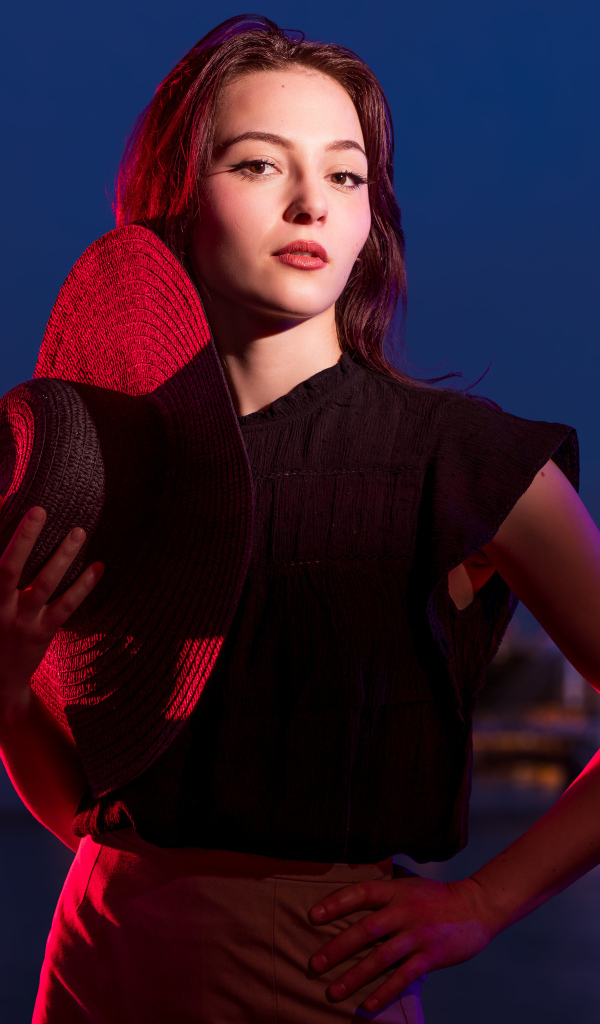 Девушка в лучах света со шляпой в руках