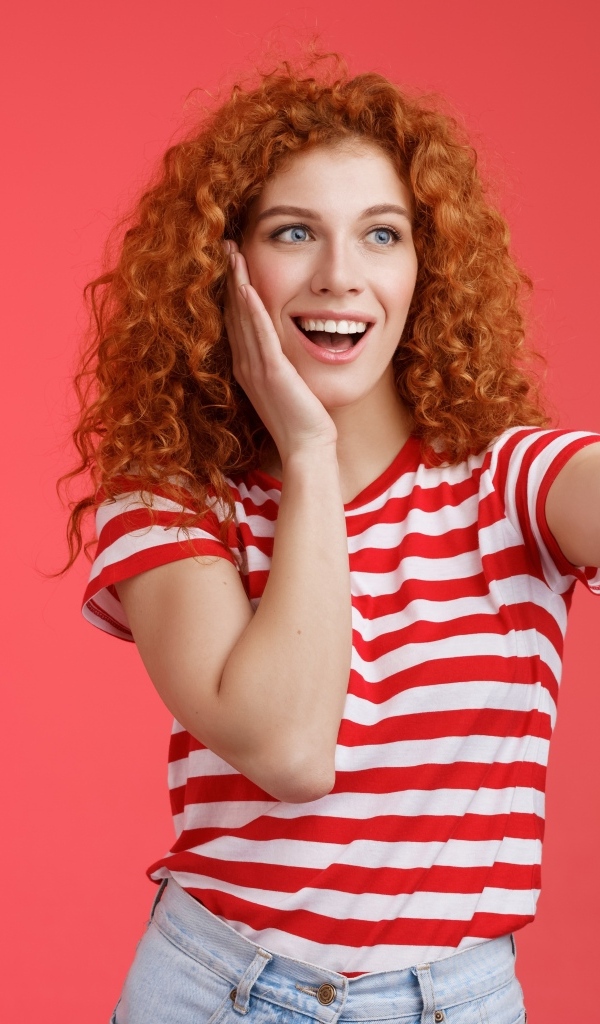 Девушка делает селфи на красном фоне