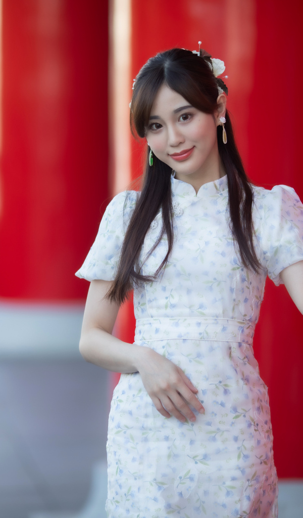 Длинноволосая азиатка позирует у красной колонны