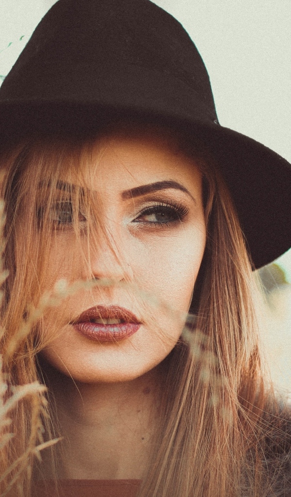 Серьезная девушка в черной шляпе 