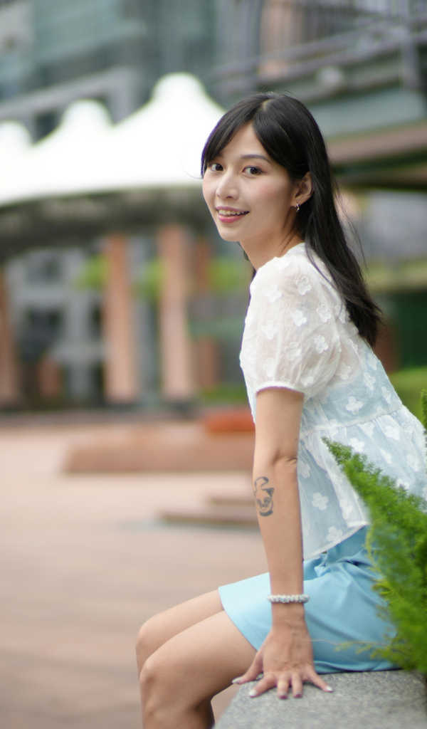 Улыбающаяся азиатка в белой блузке у дома