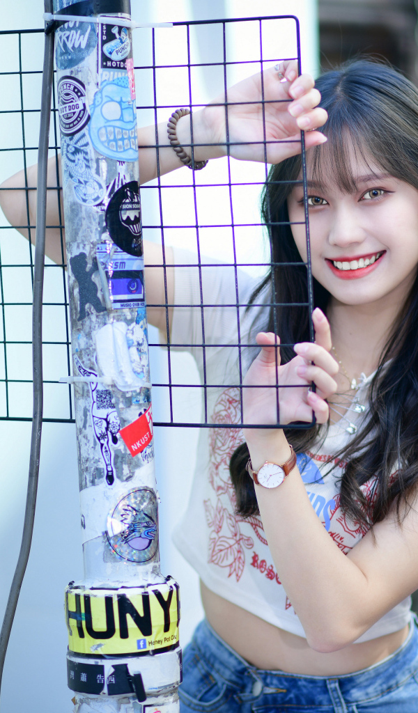 Улыбающаяся азиатка держится за сетку