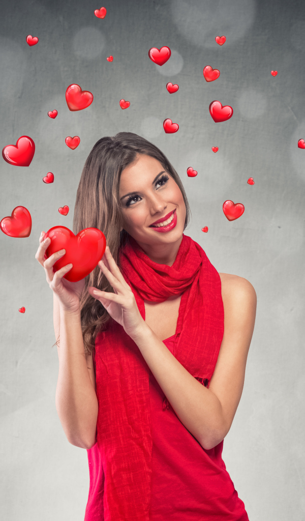 Улыбающаяся девушка в красном платье с сердечками на сером фоне