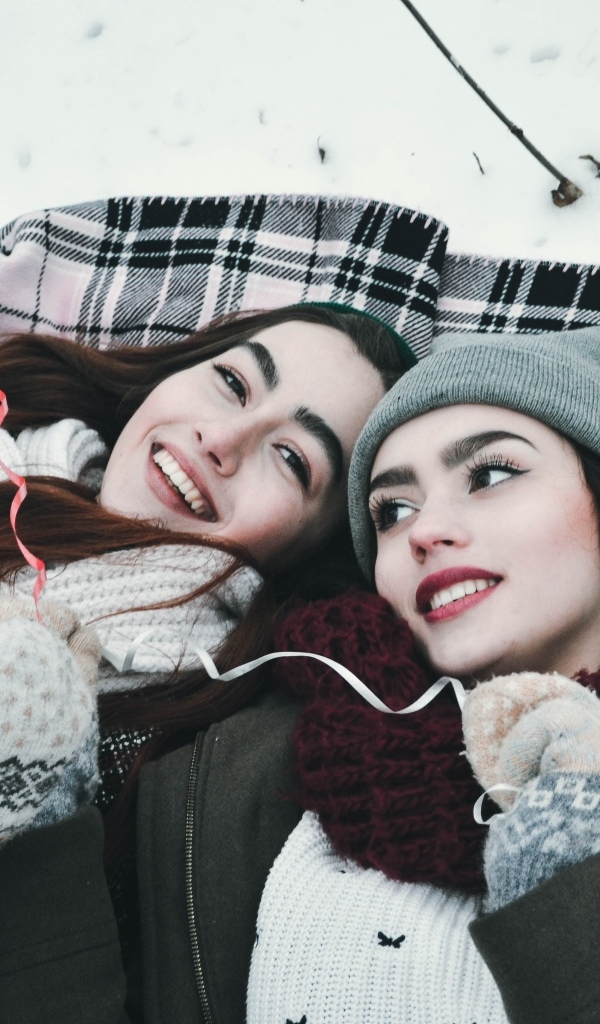 Две красивые молодые девушки лежат на снегу