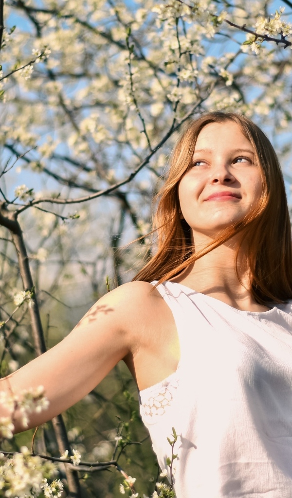 Молодая девушка у цветущего дерева весной