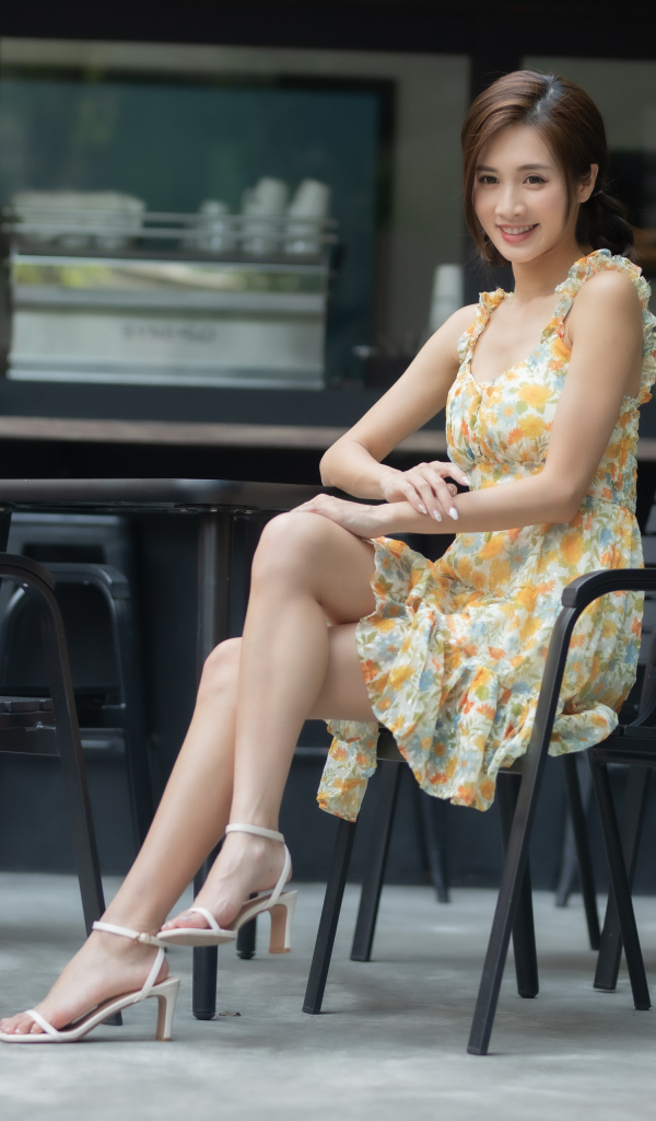 Молодая улыбающаяся азиатка за столиком в кафе