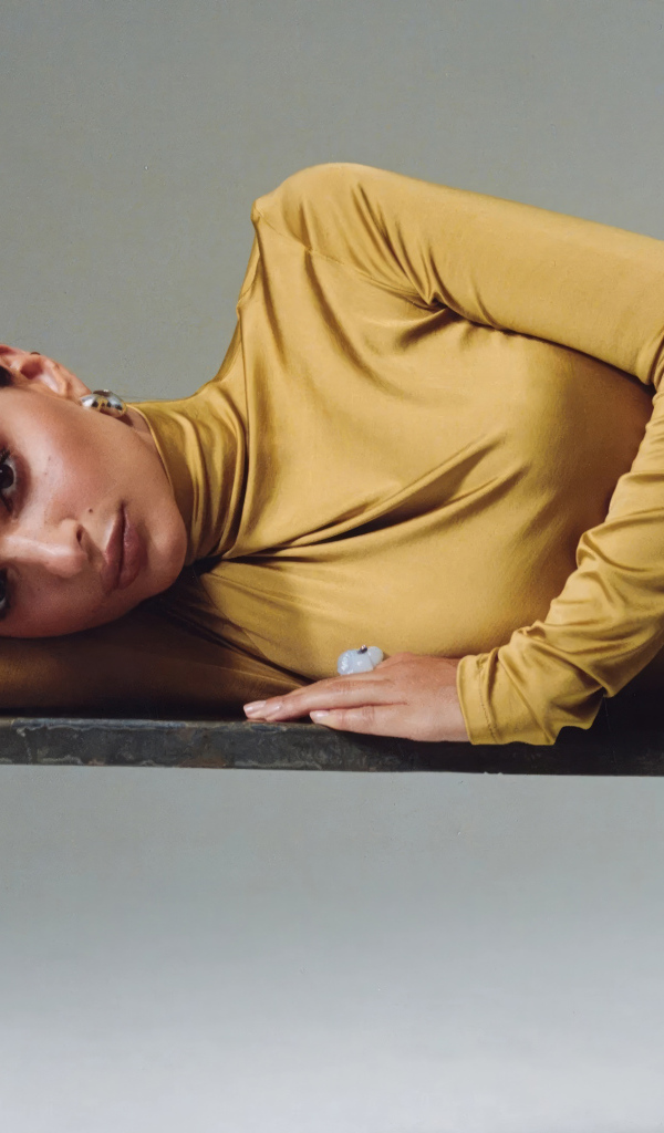 Красивая модель Эмили Ратаковски в желтом платье лежит на столе