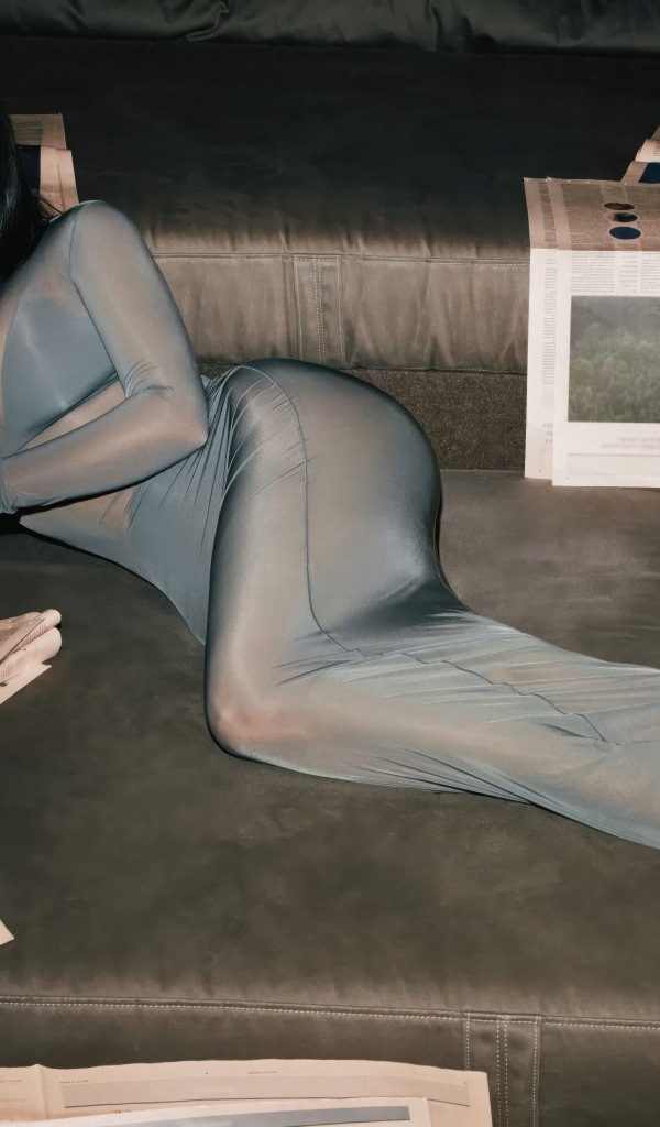 Модель Ким Кардашьян лежит на диване с газетами