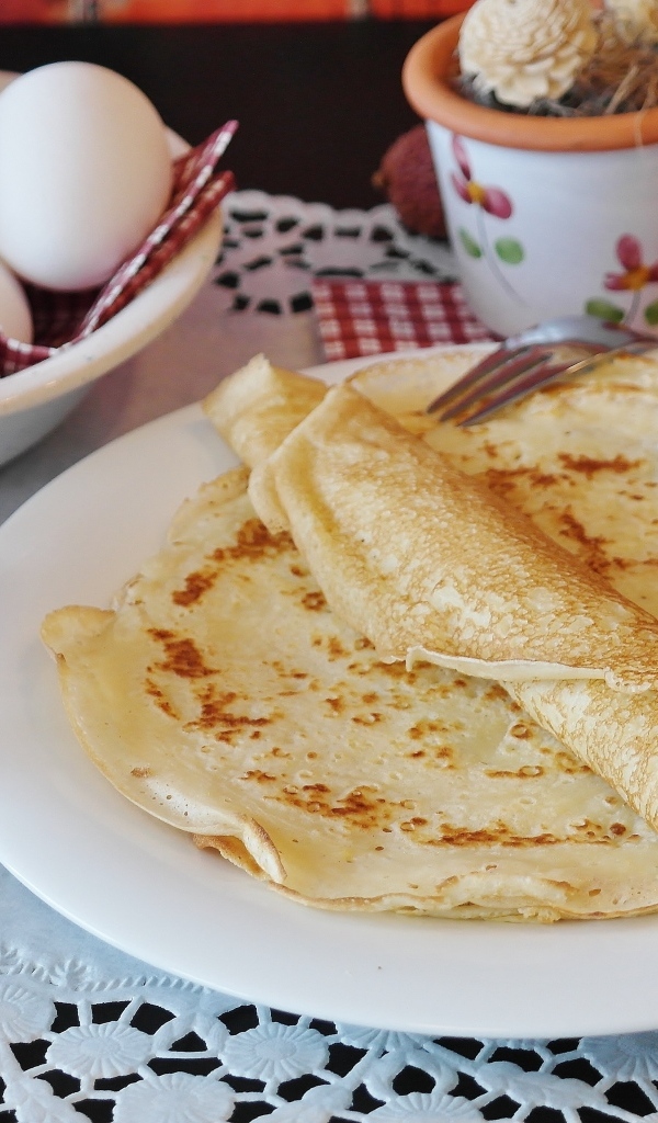 Блины на столе с яйцами и сахарной пудрой