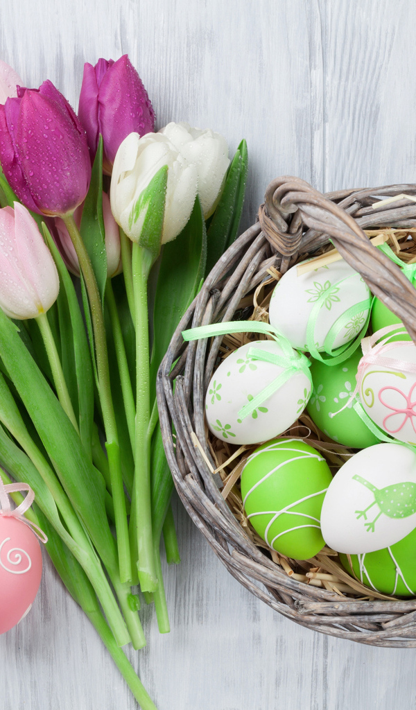 Корзина разноцветных пасхальных яиц с букетом тюльпанов