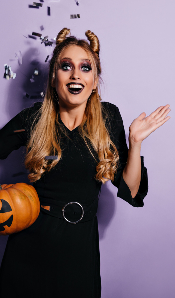 Девушка в черном костюме с тыквой на праздник Хэллоуин