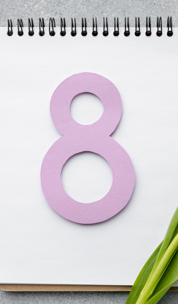 Розовая цифра 8 на блокноте с белым тюльпаном на Международный женский день 