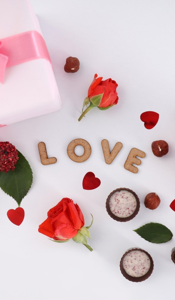 Подарок и сердечки с конфетами на столе на День Святого Валентина