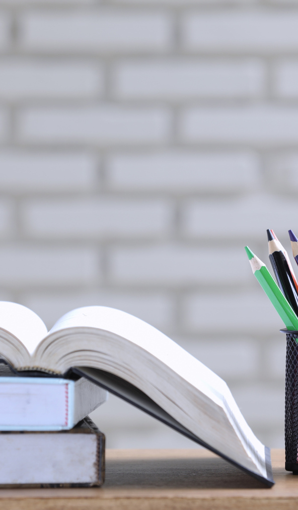 Разноцветные карандаши на столе с книгами 