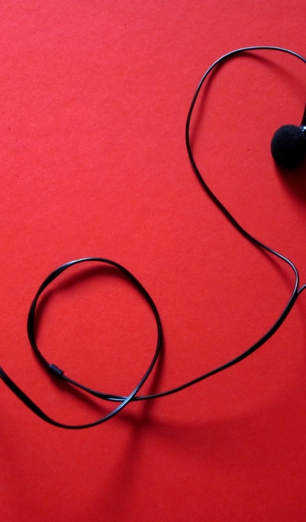 Черные наушники в форме сердца на красном фоне