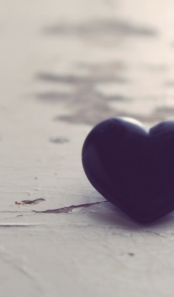 Черное каменное сердце на деревянной поверхности 