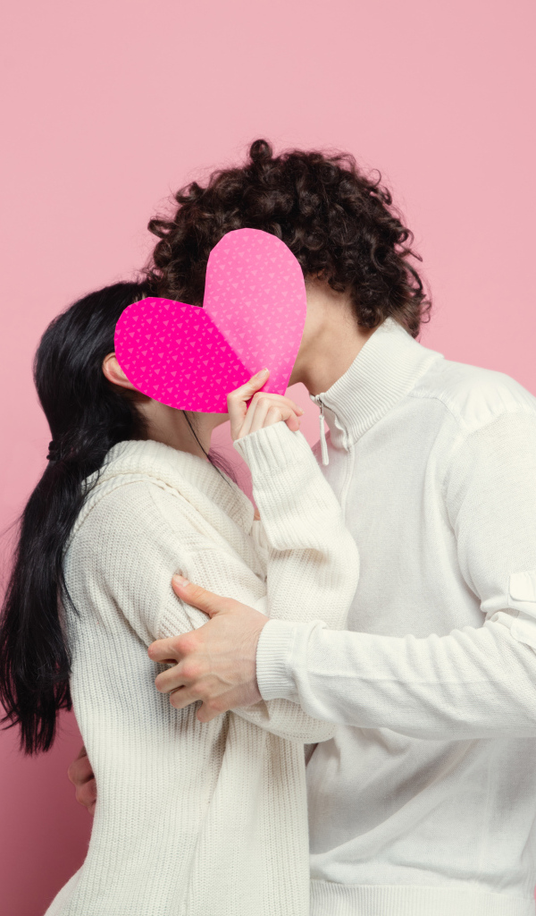 Влюбленная пара закрылась сердечком на розовом фоне