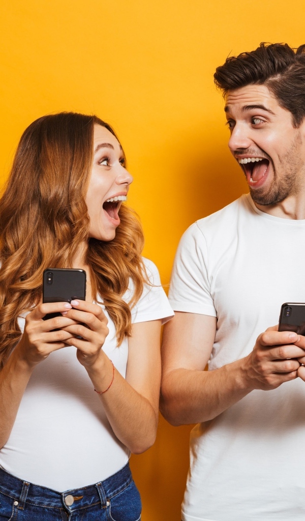 Счастливые парень и девушка с мобильными телефонами