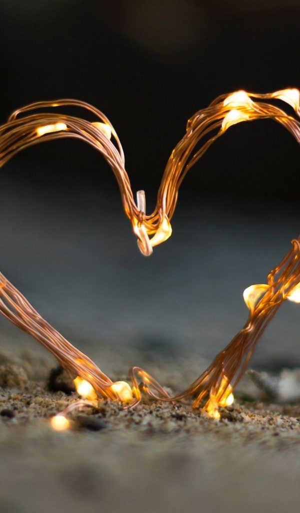 Сердце из гирлянды на песке