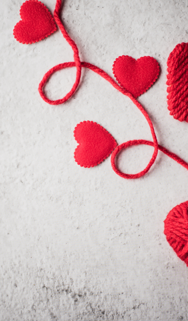 Сердечки из красной шерстяной нити на сером фоне