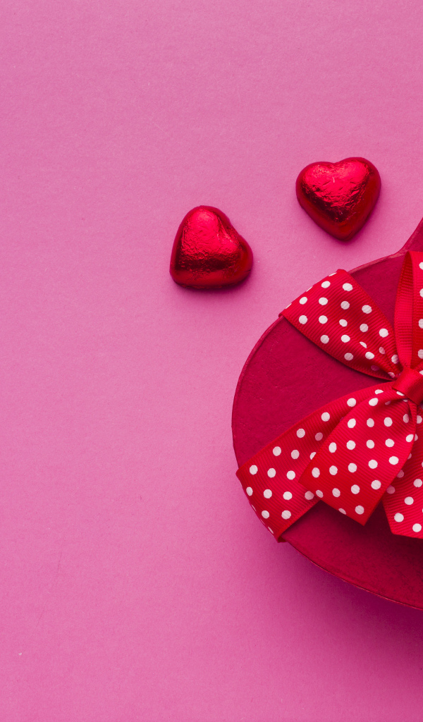 Большая красная коробка в форме сердца на розовом фоне