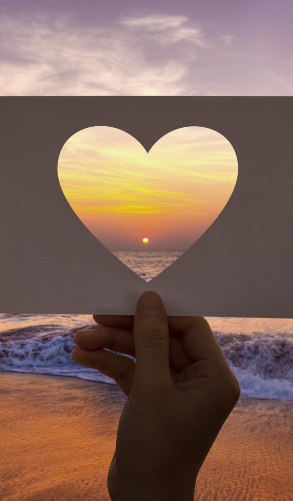 Бумажное сердце на фоне моря на закате солнца