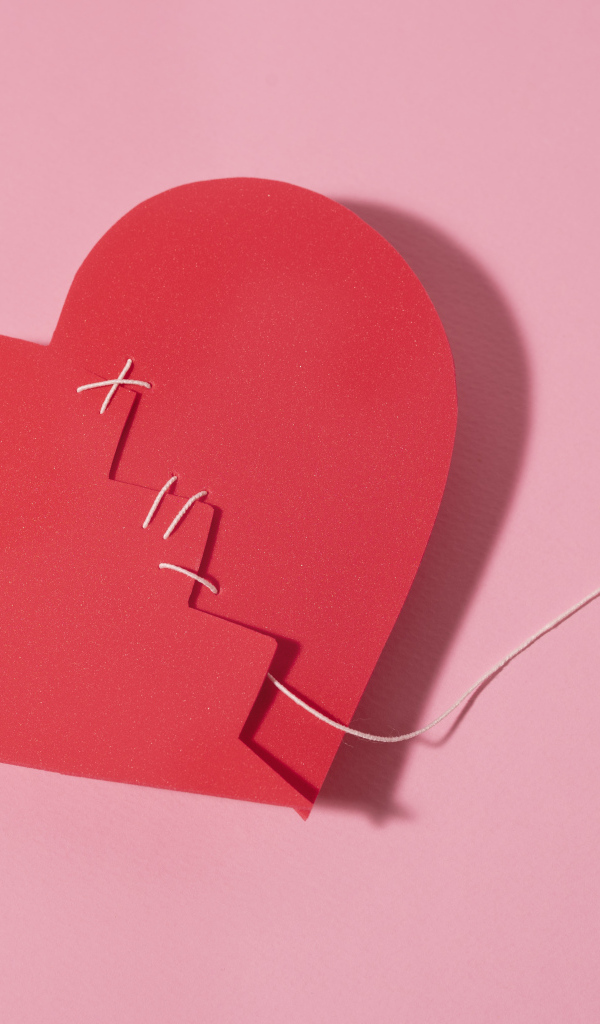 Бумажное сердце сшили нитками на розовом фоне