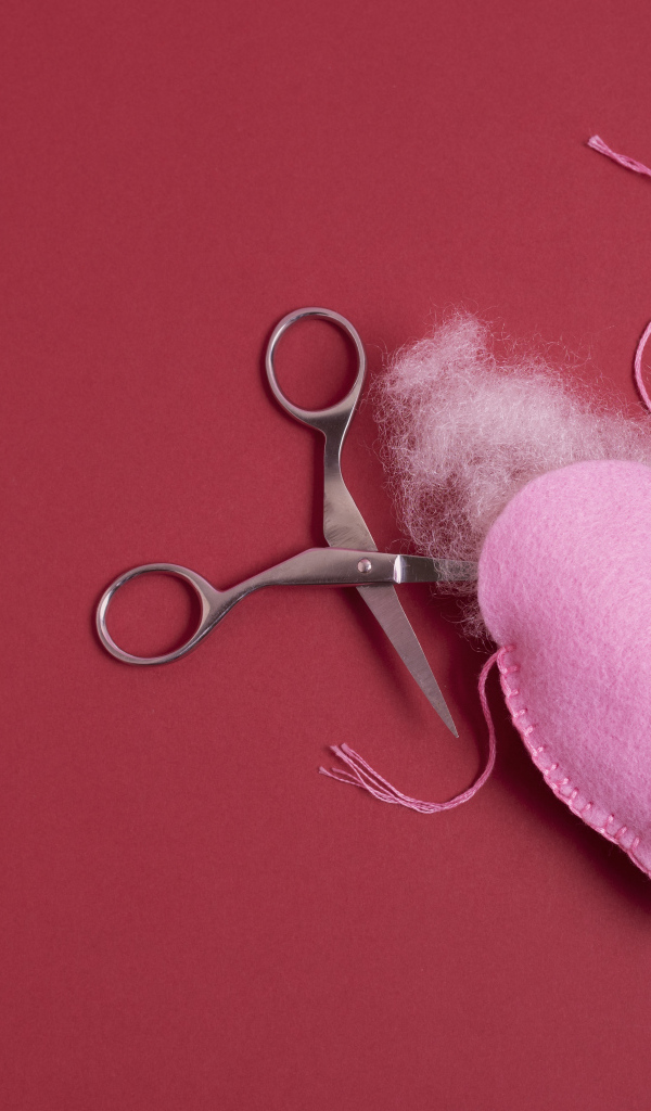 Розовое  сердце с ножницами на красном фоне