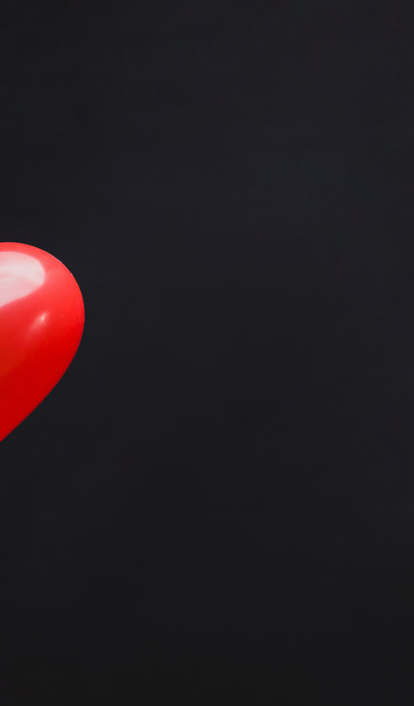 Красный шарик в форме сердца на черном фоне