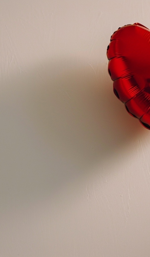 Красный шарик в форме сердца на сером фоне