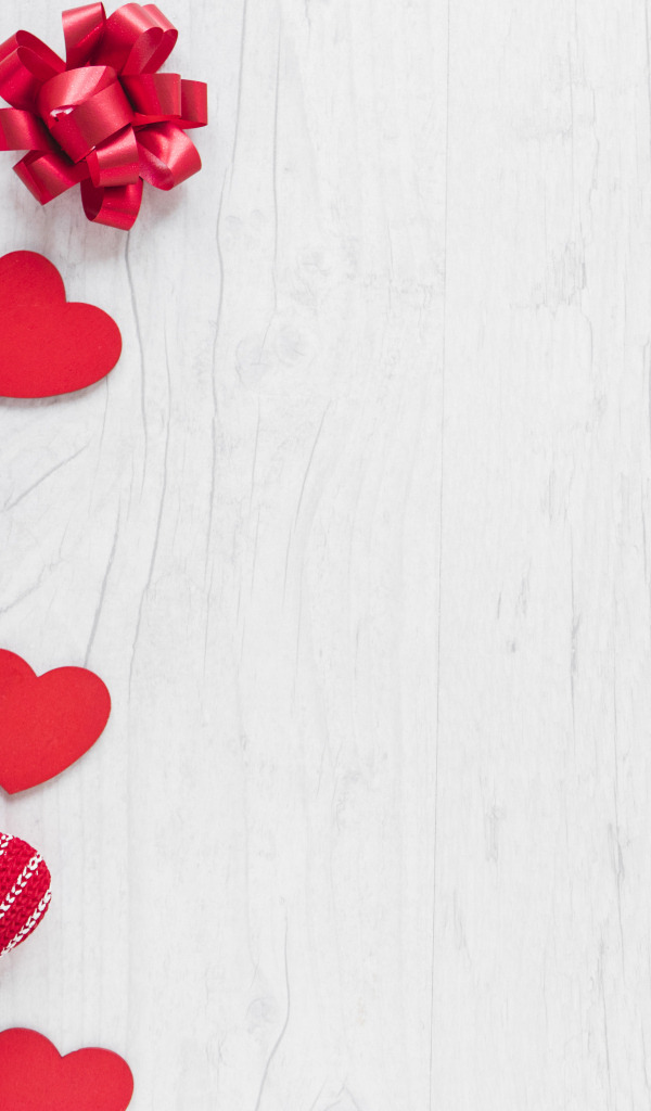 Красные сердечки с подарками и бантами на деревянном фоне