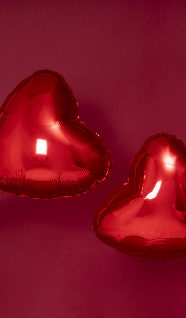 Два воздушных шара в форме сердца на красном фоне
