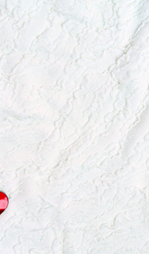 Два красных сердца из пластика на белой ткани