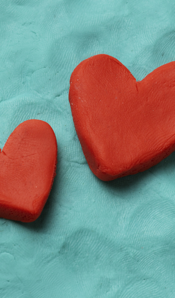 Два красных сердца из пластилина на голубом фоне