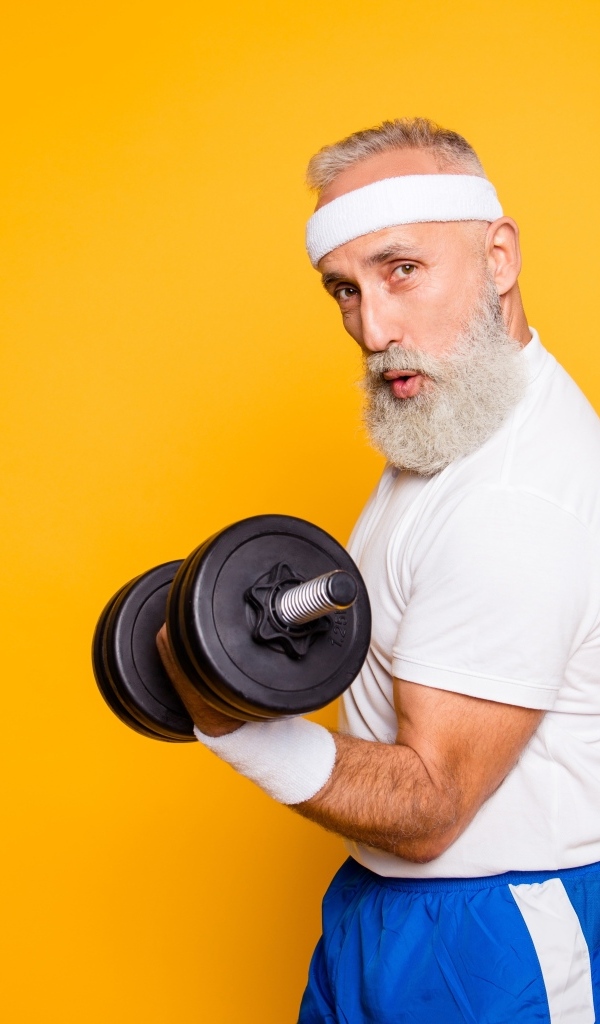 Спортивный мужчина с гантелей в руке на желтом фоне