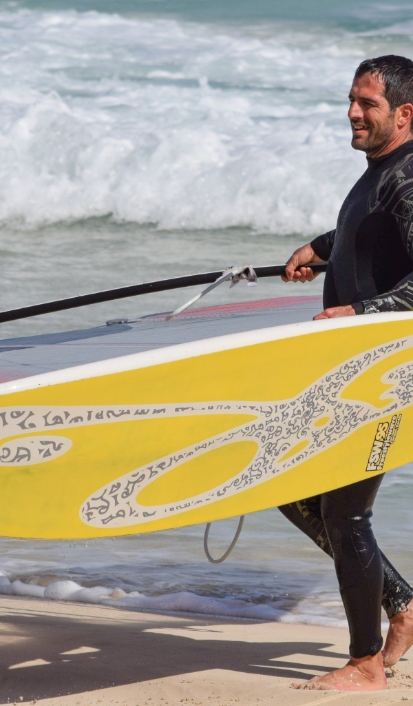 Мужчина серфер с доской на пляже