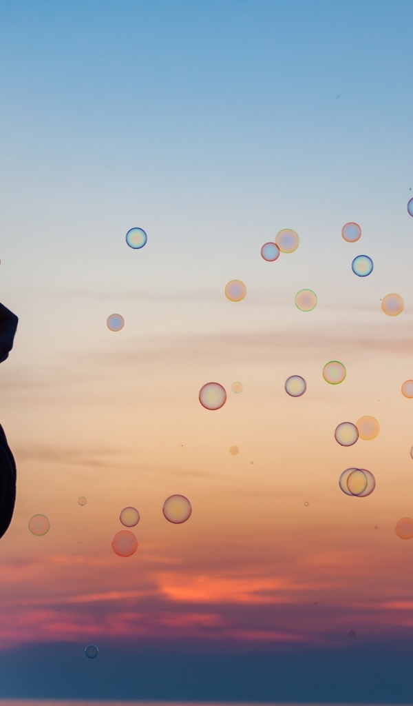 Мужчина пускает мыльные пузыри на закате