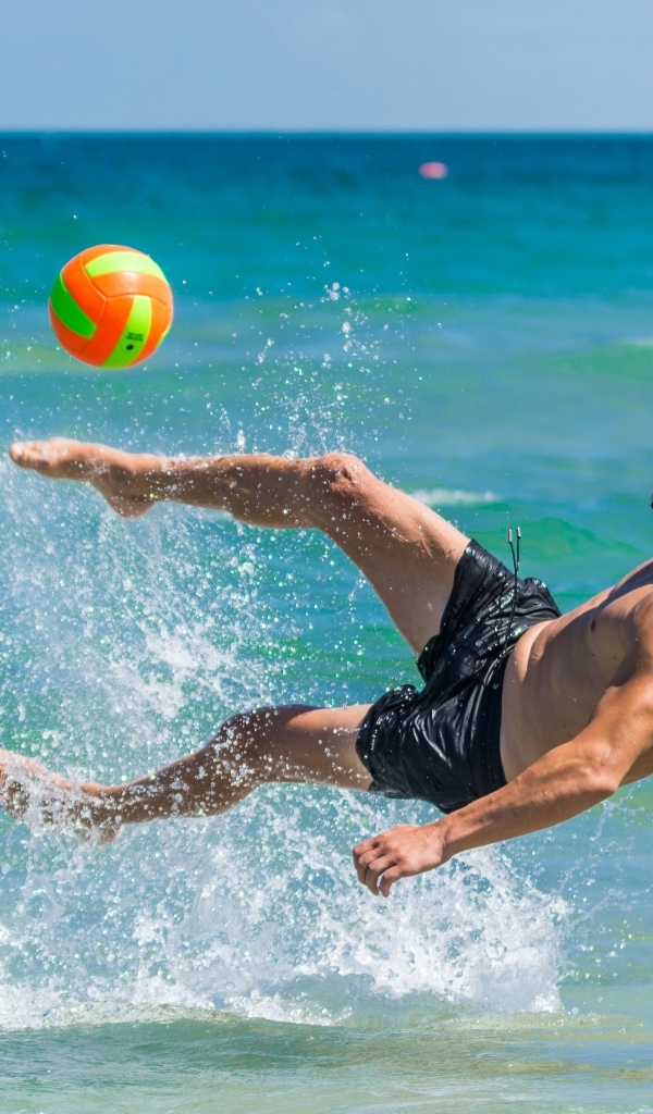 Мужчина играет в пляжный футбол