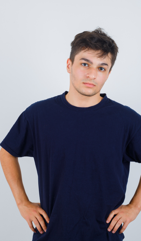 Молодой парень в синей футболке на сером фоне