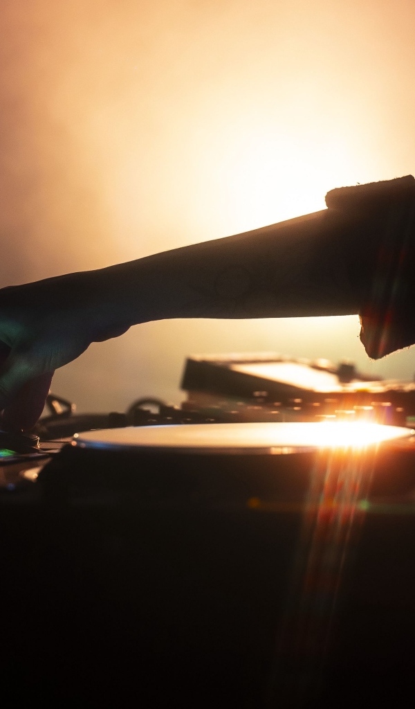 Рука диджея настраивает музыкальный пульт 