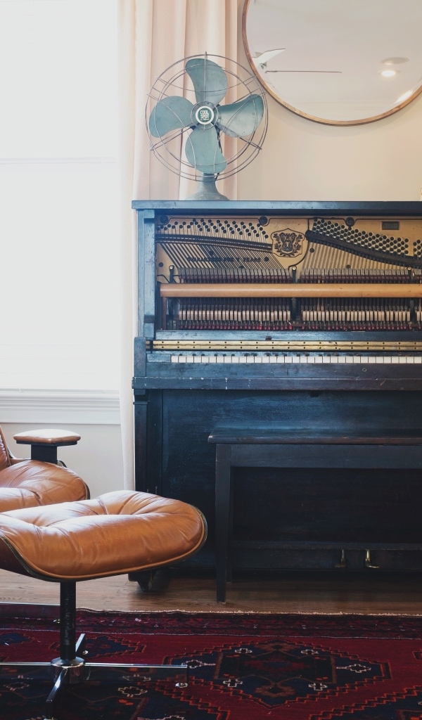 Старое пианино в комнате с кожаным креслом