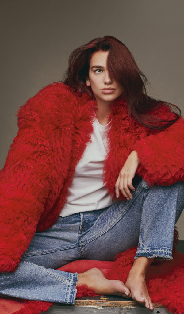 Певица Дуа Липа в красной шубе сидит на полу