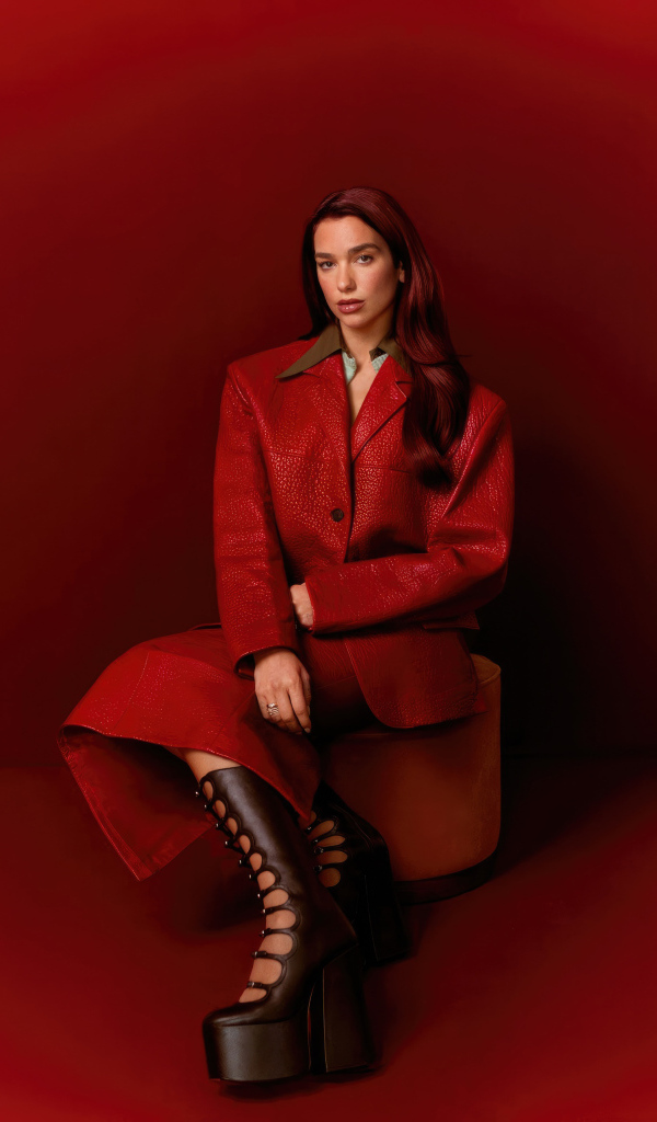 Певица Дуа Липа позирует на красном фоне