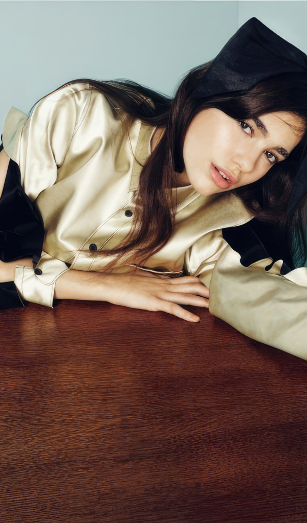 Певица Дуа Липа сидит за деревянным столом