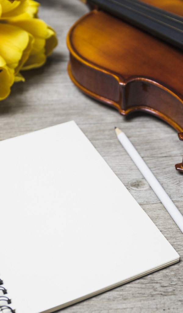 Скрипка, блокнот и желтые тюльпаны на столе